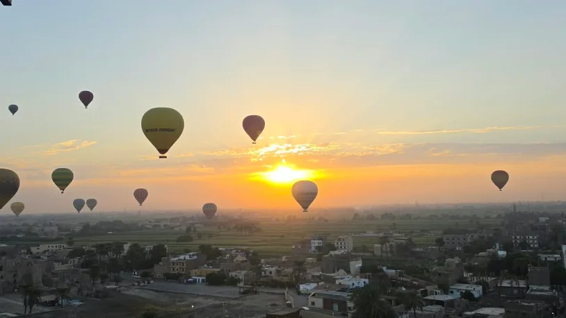 Mongolfiere all'alba sopra i villaggi e i campi verdi della riva occidentale di Luxor, viste dal cesto