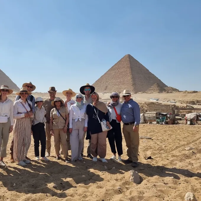 A group of guests in sun hats before the Giza pyramids