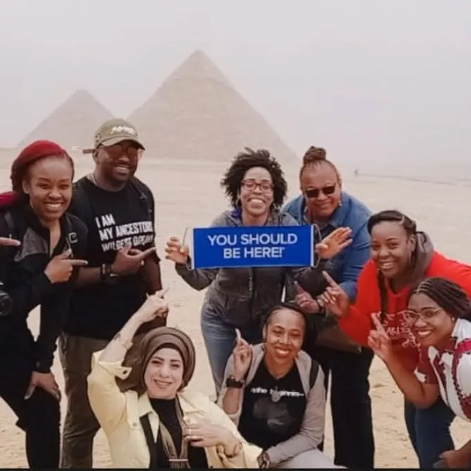 A joyful group of guests holding a sign at the Giza pyramids