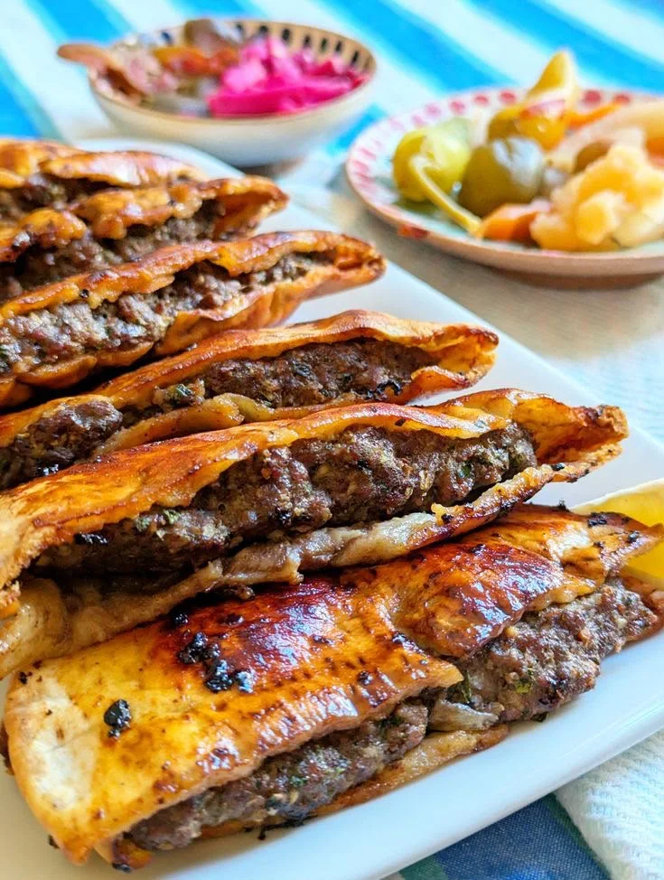 Hawawshi terbelah yang memperlihatkan daging cincang berbumbu, dengan acar di sampingnya