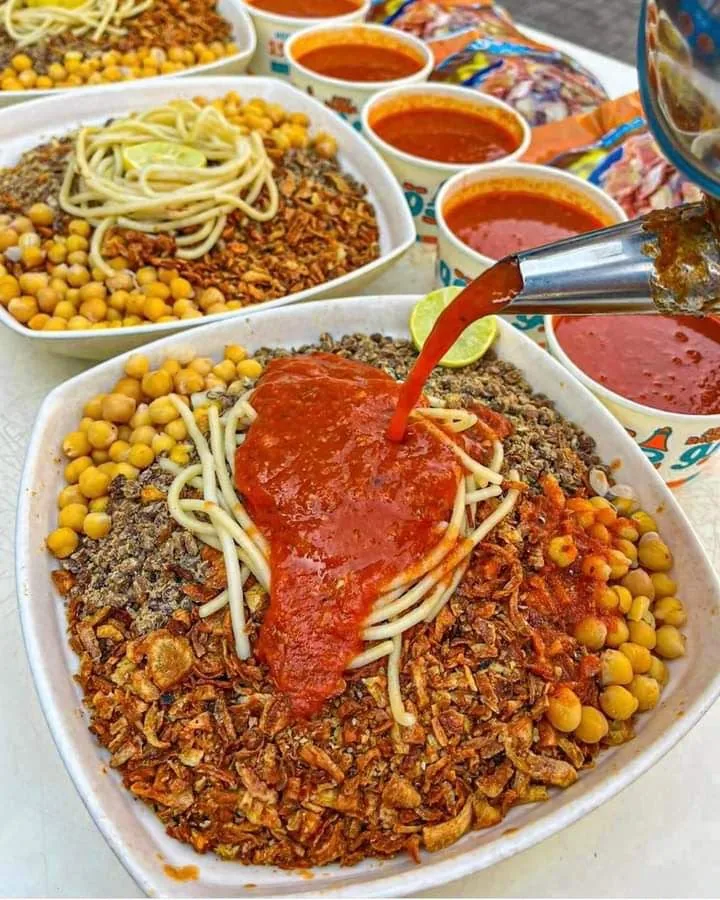 Koshari, with tomato sauce poured over pasta, lentils, chickpeas and crisp fried onions