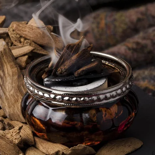 Chips of oud smouldering in a burner, more agarwood beside it