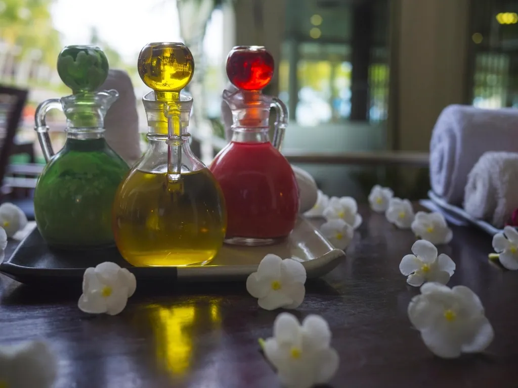 Massage oils in glass bottles with white flowers and rolled towels