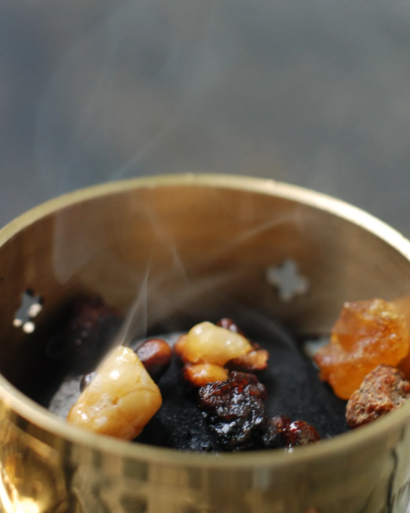 Tears of frankincense and dark myrrh smouldering on charcoal in a brass burner