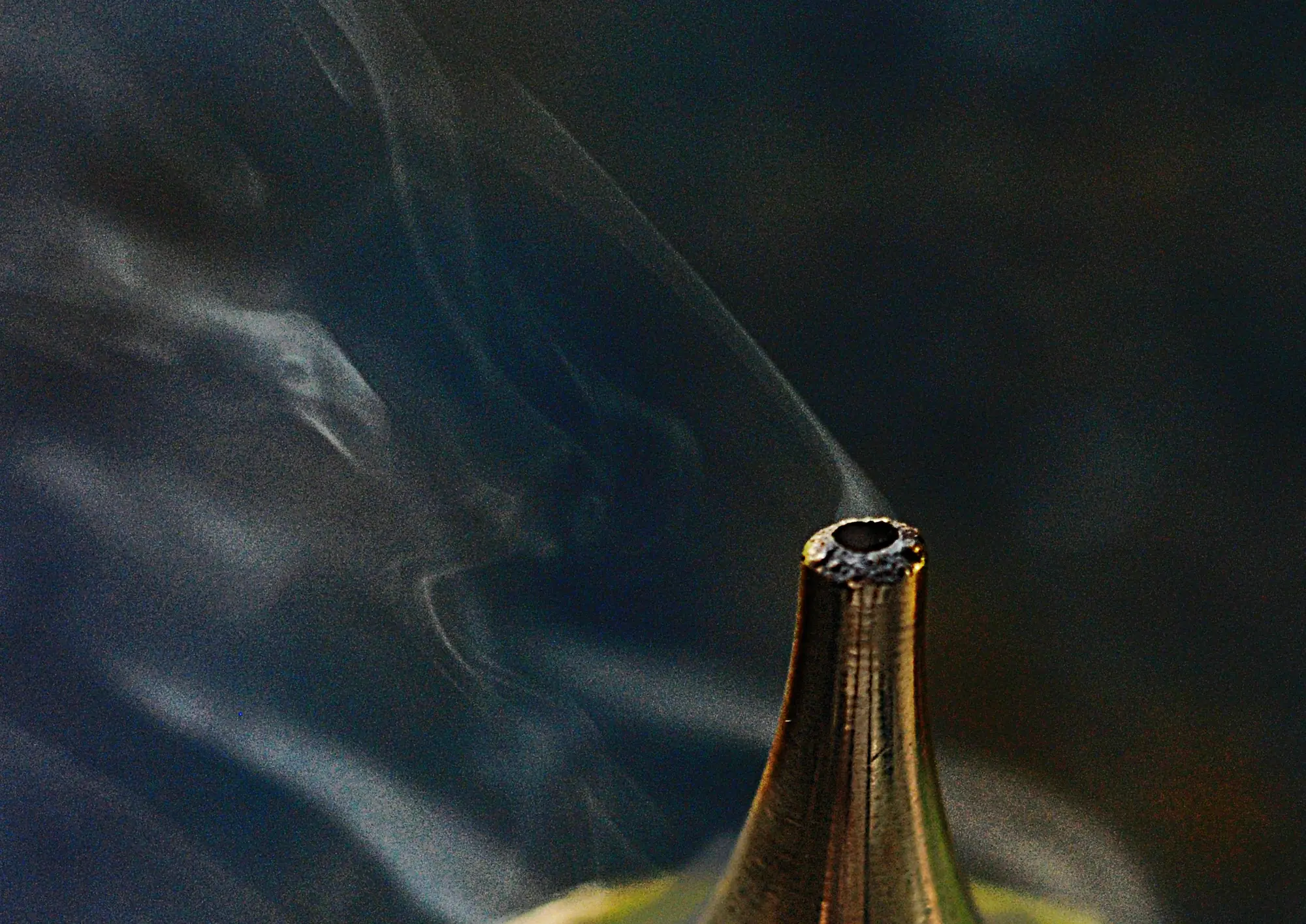 Smoke curling from the spout of an engraved brass incense burner